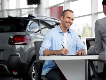 Ein Mann unterzeichnet den Kaufvertrag beim Autoankauf Hassee